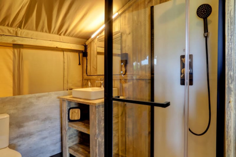 Bagno moderno in tenda safari con doccia, lavandino e wc al Camping Dal van de Mosbeek, Paesi Bassi.