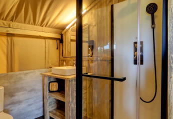 Bagno moderno in tenda safari con doccia, lavandino e wc al Camping Dal van de Mosbeek, Paesi Bassi.