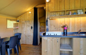 Vista interior de la tienda safari con cocina y comedor en Camping Dal van de Mosbeek, Países Bajos.
