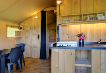 Vista interior de la tienda safari con cocina y comedor en Camping Dal van de Mosbeek, Países Bajos.