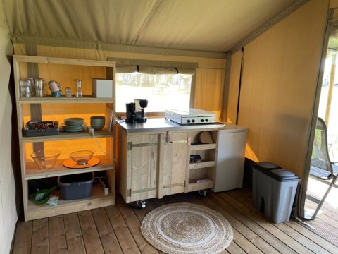 Coin cuisine dans une tente Safari au Minicamping Falkenborg, Pays-Bas, avec étagères et réfrigérateur.