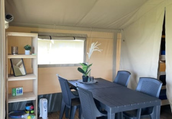 Interior de la tienda Safari en Minicamping Falkenborg, Países Bajos, con mesa, sillas y estantería.