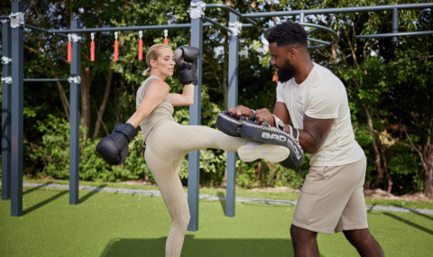 Vrouw traint kickboksen met trainer in een buitenfitnessruimte bij Brinckerduyn vakantiepark in Friesland.