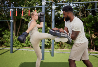 Vrouw traint kickboksen met trainer in een buitenfitnessruimte bij Brinckerduyn vakantiepark in Friesland.