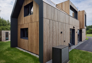 Moderne houten vakantiewoning met zwarte accenten in Brinckerduyn, Friesland, Nederland, op groene grasmat.