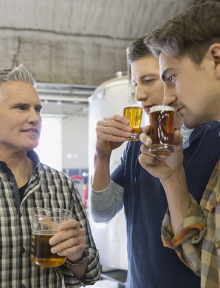 Drei Männer probieren verschiedene Biersorten in einer Brauerei bei Bocholt in Limburg, Belgien.