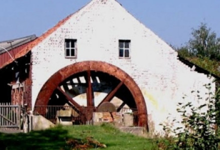 Ein altes Mühlengebäude mit großem Wasserrad in ländlicher Umgebung bei Bocholt, Limburg, Belgien.