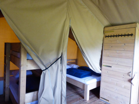Innenansicht eines Safari-Zeltes mit Etagenbett, Einzelbett und Holzboden auf Minicamping de Vrolijke Flierefluiter.
