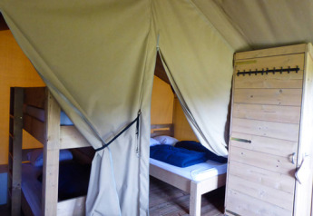 Inside of a safari tent with bunk bed, single bed, and wooden floor at Minicamping de Vrolijke Flierefluiter.