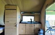 Interieur van safaritent met houten keuken en terras op Minicamping de Vrolijke Flierefluiter.