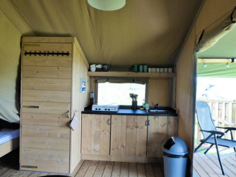 Interieur van een safaritent met houten keuken en terras bij Minicamping de Vrolijke Flierefluiter.