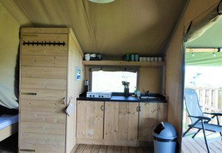 Interieur van een safaritent met houten keuken en terras bij Minicamping de Vrolijke Flierefluiter.