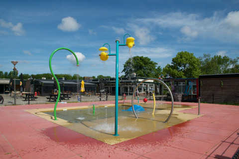 Waterspeelplaats met sproeiers en speeltoestellen bij Camping de Krabbeplaat, Zuid-Holland, Nederland.