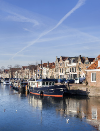 Vista del canal en Brielle, Países Bajos, con barcos y casas tradicionales bajo el cielo despejado.
