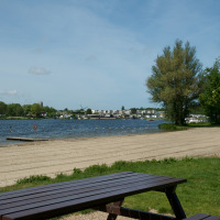 Mesa de picnic junto a una playa de arena en un lago tranquilo cerca de Brielle, Holanda Meridional, Países Bajos.