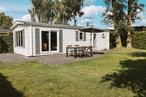 Veluwe lodge met moderne witte gevel, terras en tuin op vakantiepark De Boshoek in Nederland.