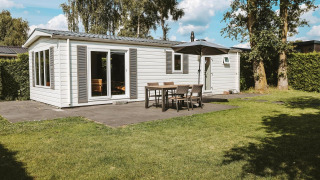 Lodge Veluwe con fachada blanca moderna, terraza y jardín en el Holiday park De Boshoek, Países Bajos.