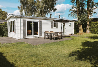 Veluwe lodge met moderne witte gevel, terras en tuin op vakantiepark De Boshoek in Nederland.