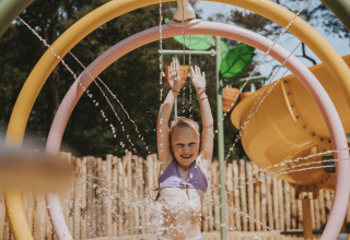 Een meisje speelt vrolijk in een waterspeeltuin bij Beerze Bulten vakantiepark in Overijssel, Nederland.