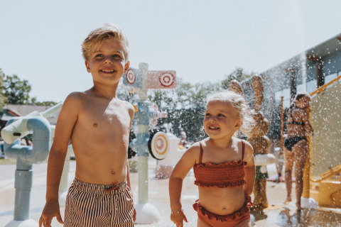Twee jonge kinderen spelen vrolijk in het waterpark van Beerze Bulten, een vakantiepark in Overijssel.