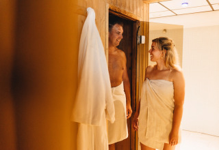 Twee mensen in handdoeken ontmoeten elkaar bij de ingang van een sauna in Beerze Bulten, Overijssel.