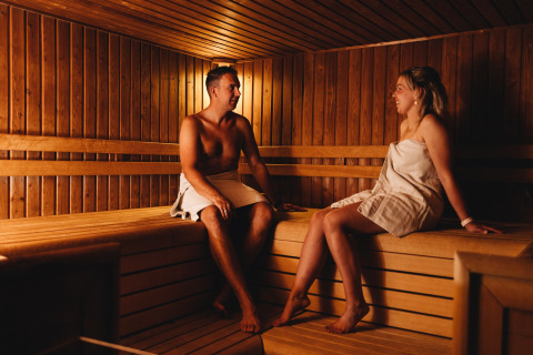 Twee mensen ontspannen en praten samen in een houten sauna bij Beerze Bulten vakantiepark, Overijssel.