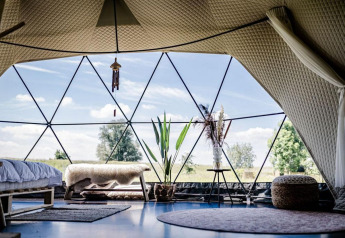 Interno del Cast Away Dome a TinyParks Cast Away nei Paesi Bassi con arredi moderni e vista sulla natura.