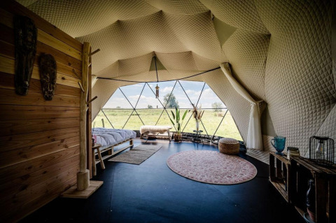 Intérieur d'une Cast Away Dome chez TinyParks Cast Away aux Pays-Bas, avec grande baie vitrée et vue champêtre.