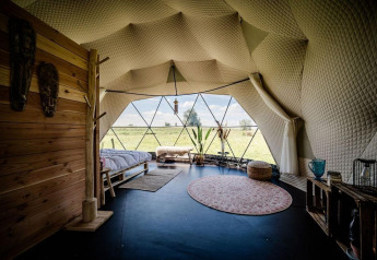 Interieur van de Cast Away Dome bij TinyParks Cast Away in Nederland, met glazen wand en uitzicht op natuur.