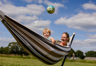 Moeder en kind genieten samen in een hangmat op CharmeCamping De Regge-Vallei, Overijssel, Nederland.