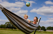 Moeder en kind genieten samen in een hangmat op CharmeCamping De Regge-Vallei, Overijssel, Nederland.