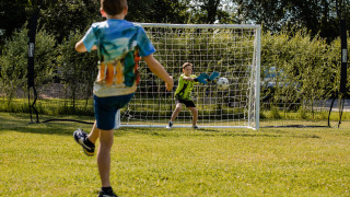 Kinderen spelen voetbal op het grasveld bij CharmeCamping De Regge-Vallei in Overijssel, Nederland.