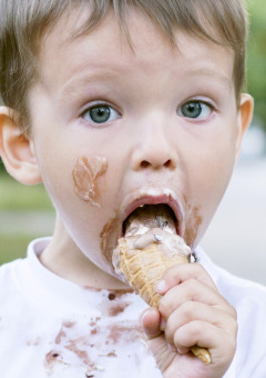 Jonge jongen met ijs op zijn gezicht eet een ijsje op een vakantiepark met glampingaccommodaties.