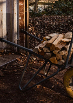 Eine Schubkarre voller Brennholz steht neben einem Schuppen im Wald von Limburg, Belgien.