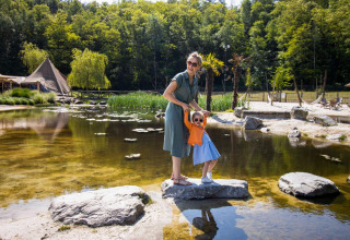 Mutter und Tochter mit Sonnenbrillen genießen den Tag am Teich im Ferienpark Cosy Cabins, Limburg, Belgien.