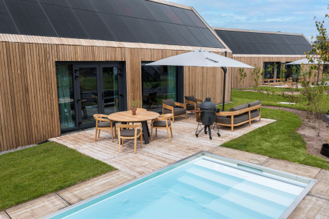 Moderne vakantielodge met houten gevel, terras, tuinset en zwembad in De Weelderik, Gelderland.