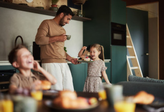 Un padre e i suoi due figli fanno colazione insieme in cucina al villaggio turistico De Weelderik, Gelderland.
