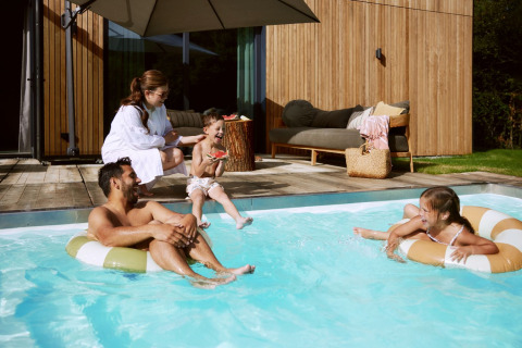 Familia divirtiéndose y relajándose en la piscina de De Weelderik, parque vacacional en Gelderland, Países Bajos.