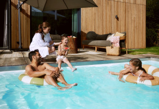 Famiglia che si rilassa e si diverte in piscina al parco vacanze De Weelderik, Gelderland, Paesi Bassi.