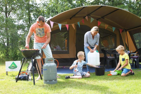 Gezin kampeert gezellig bij een safaritent op CharmeCamping De Regge-Vallei in Nederland, zomer.