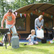 Familie nyder camping foran en safaritelte på CharmeCamping De Regge-Vallei i Holland, sommerdag.
