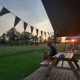 Person sidder ved et picnicbord foran en glamping telt ved solnedgang på CharmeCamping De Regge-Vallei.