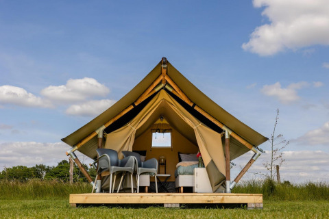 Tienda safari en CharmeCamping De Regge-Vallei, Países Bajos, con muebles modernos y cielo azul.