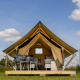 Safari telt ved CharmeCamping De Regge-Vallei i Holland med moderne møbler under en blå himmel.