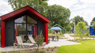 Foto de un chalet de caza en Holiday park Ackersate, Países Bajos, rodeado de naturaleza y cabañas modernas.