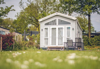 Et lille hus ved Holiday park Ackersate i Holland, omgivet af grøn natur og udendørs siddepladser.