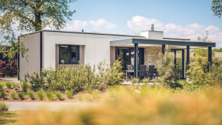 Villa de vacaciones moderna con sauna en Holiday park Ackersate, Países Bajos, rodeada de vegetación.