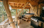 Terraza de casa en el árbol con tina de madera y barbacoa en Cosy Cabins, bosque de Limburgo, Bélgica.