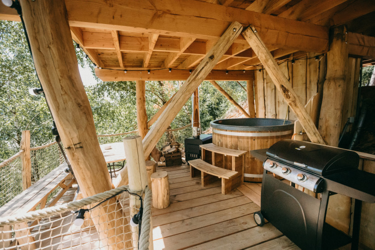 Treehouse terrace with wooden hot tub and grill at Cosy Cabins in the forest of Limburg, Belgium.