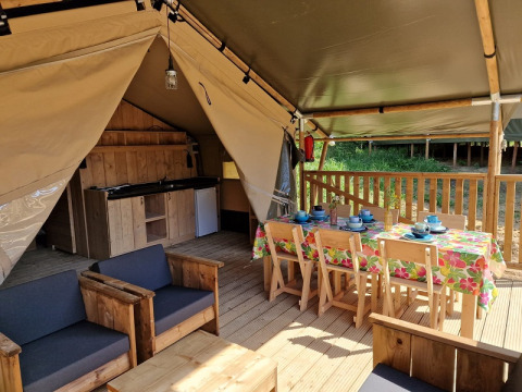 Interieur van een safaritent met houten meubels, eettafel en kitchenette bij Domaine La Sauzette, Frankrijk.
